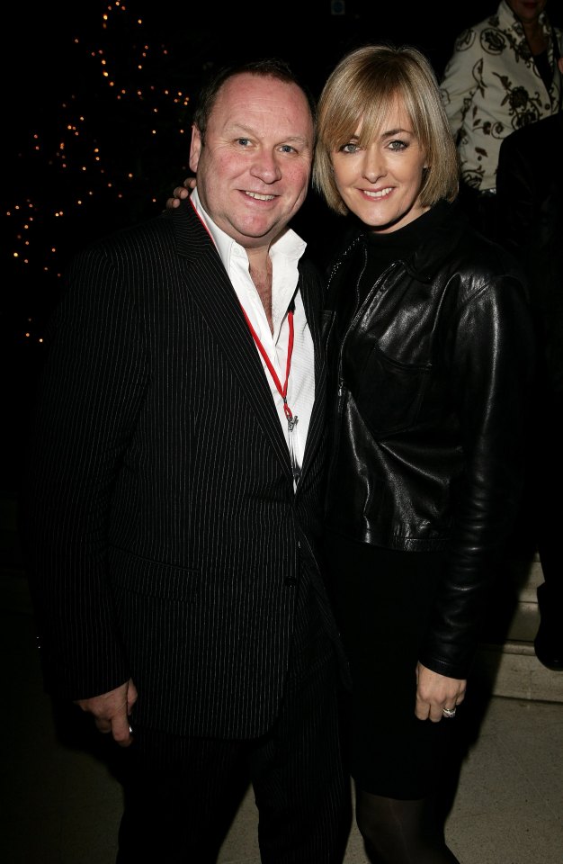 a man in a suit and a woman in a leather jacket pose for a picture