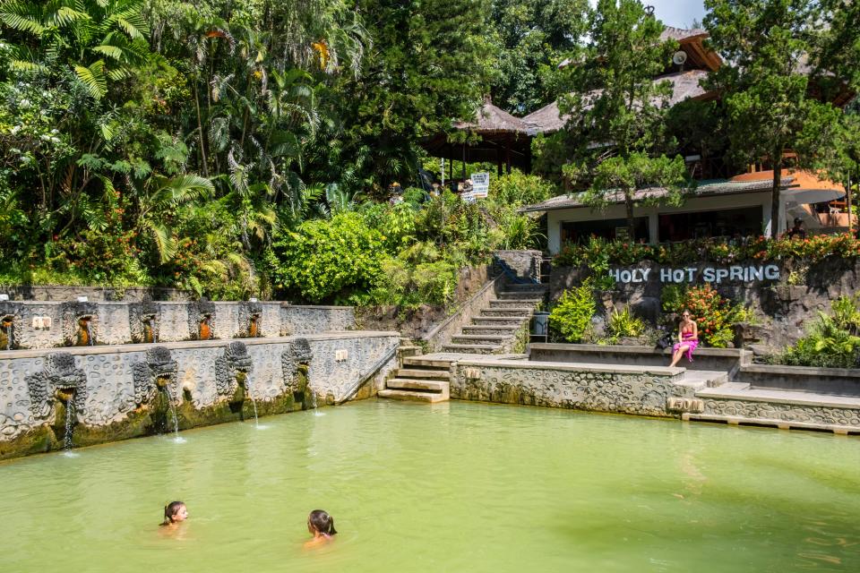 two people are swimming in a pool that says holy hot spring