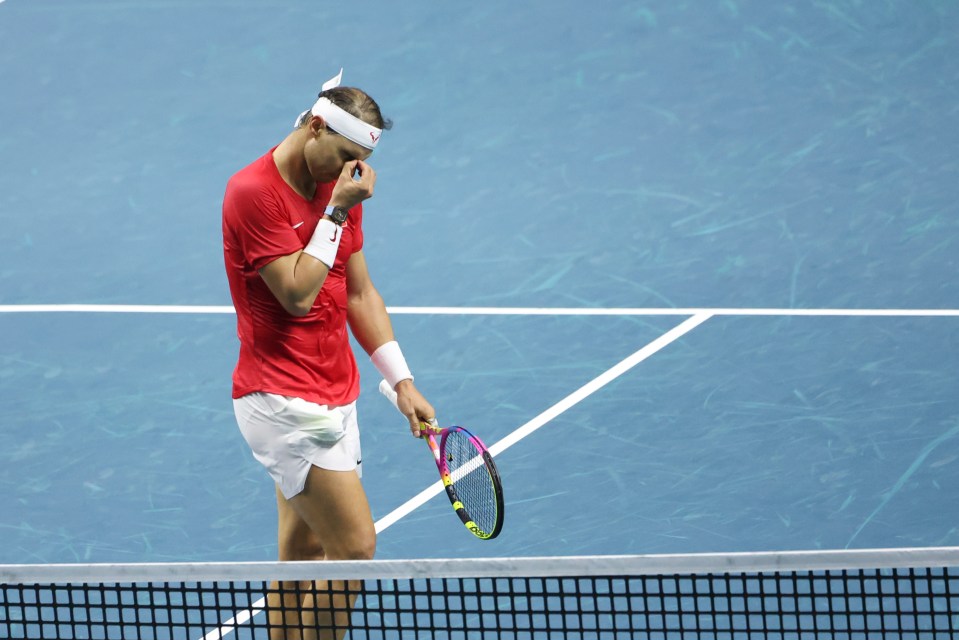 a man wearing a red shirt and white headband holds a tennis racquet