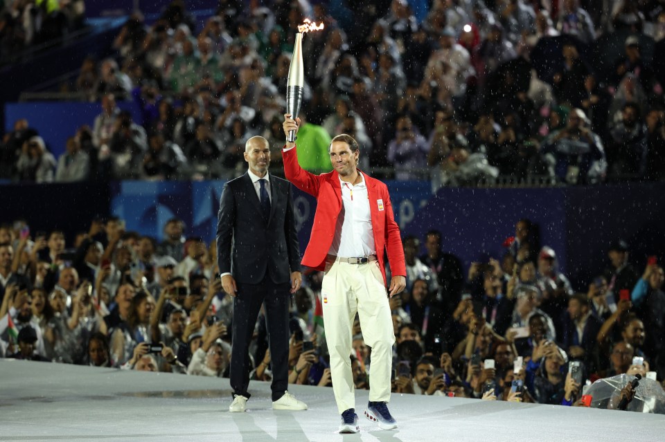 a man in a red jacket holds a torch in front of a crowd