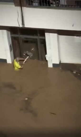 A teacher was caught on video smashing in a glass door during Spain's flooding