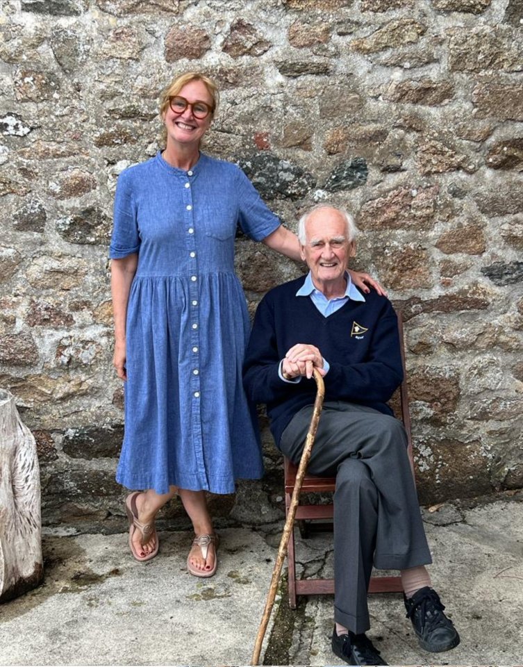 a woman in a blue dress stands next to an older man with a cane