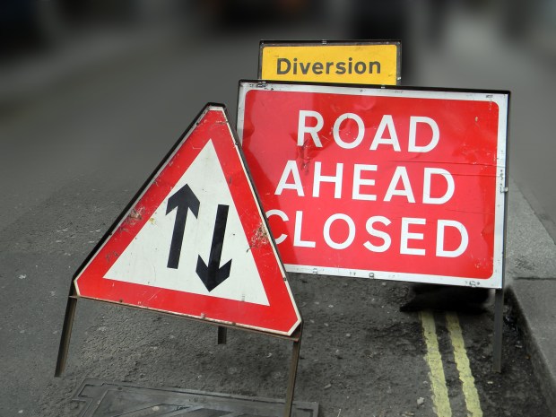 a red and white sign that says road ahead closed