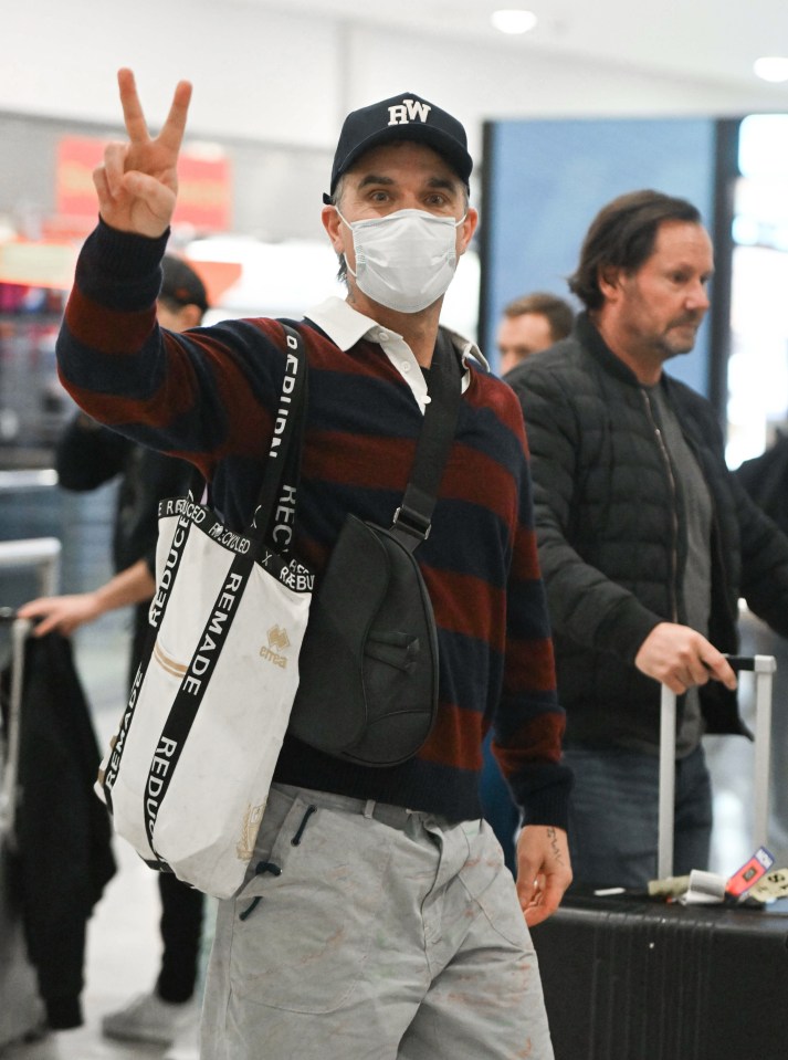 a man wearing a mask giving a peace sign