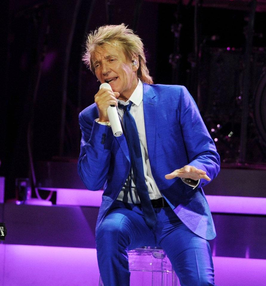 a man in a blue suit is singing into a microphone