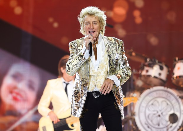 a man singing into a microphone in front of a drum set