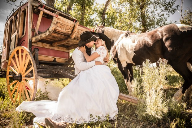 a bride and groom kiss in front of a horse drawn carriage