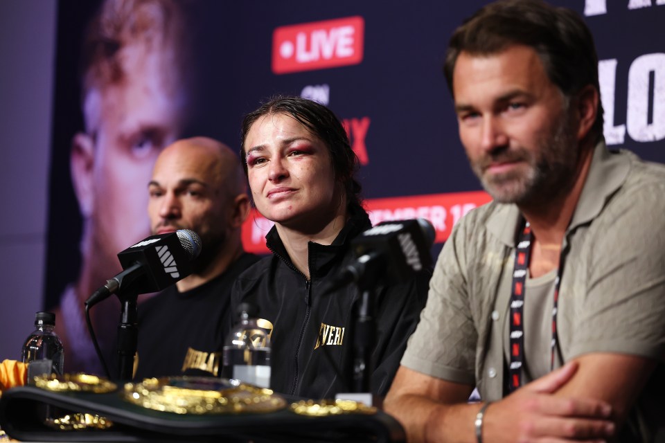 a woman wearing a black everlast jacket sits in front of a microphone