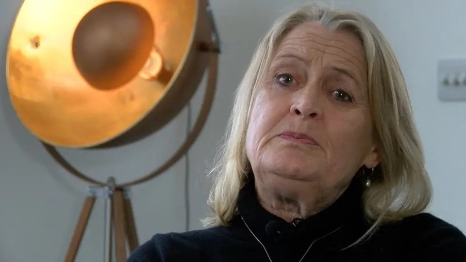 a woman is sitting in front of a lamp and looking at the camera .