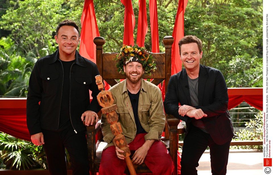 three men are posing for a picture with one wearing a crown