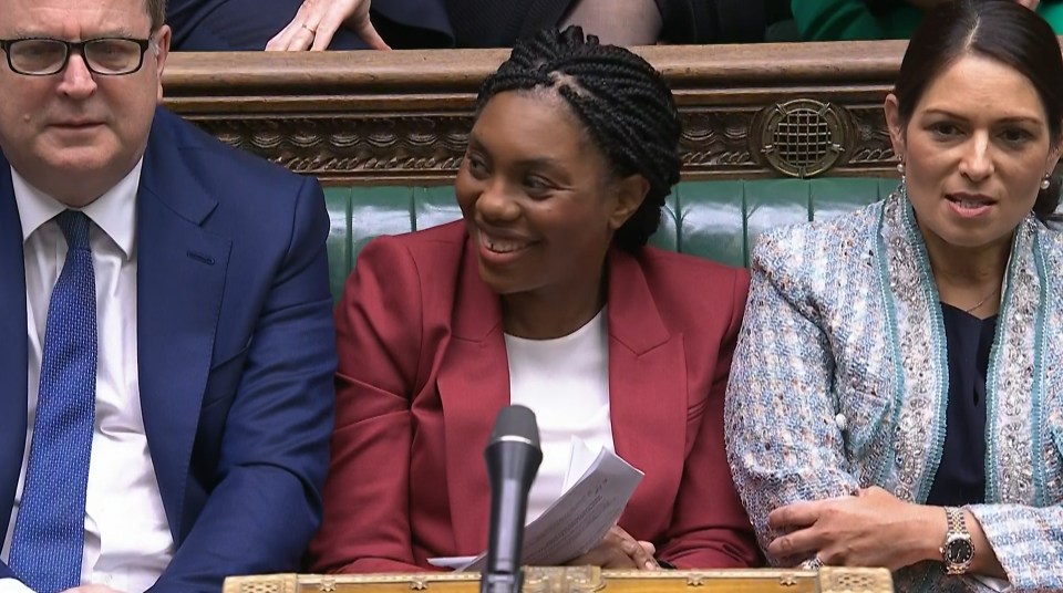 a woman in a red jacket sits between two men in suits