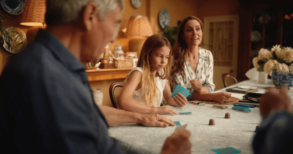 a little girl is playing a game of cards with her family