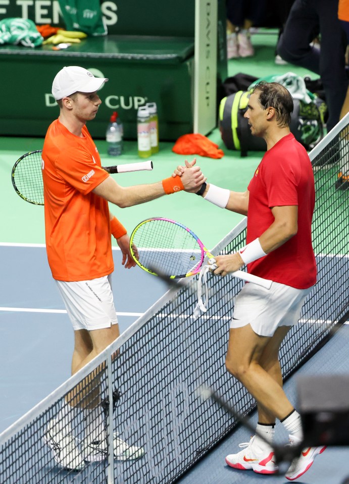 two tennis players shake hands on a court with a sign that says d cup in the background