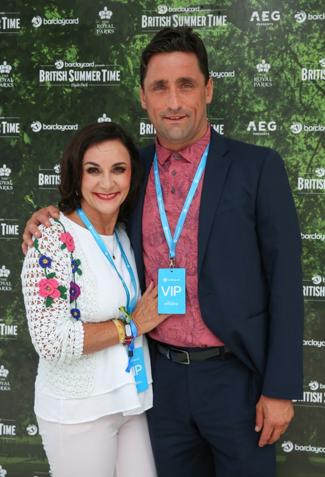 a man and woman pose in front of a green wall that says british summer time