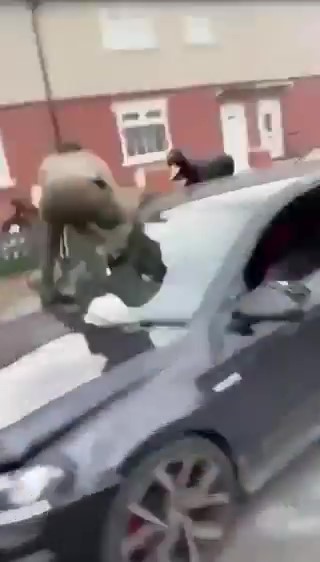 One of the group climbs over the bonnet of the car to join the attack