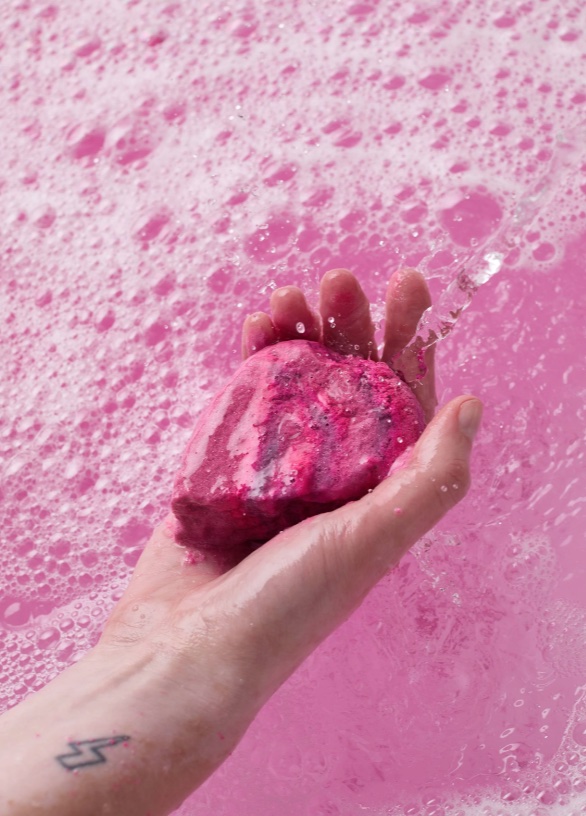 a person with a tattoo on their arm is holding a pink soap bar