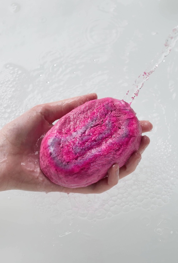 a person is holding a pink soap bar in their hand