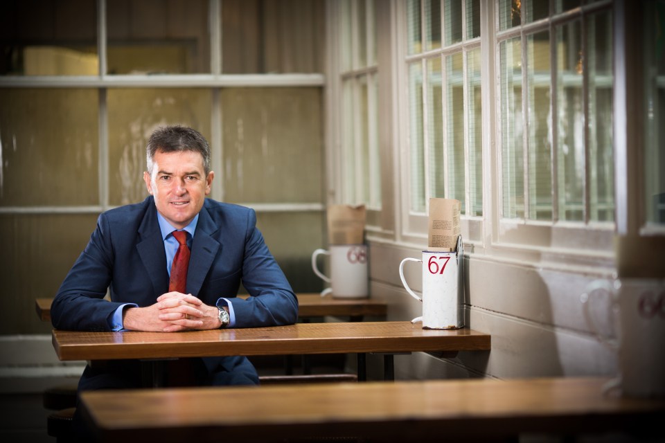 a man sits at a table with a cup that says 67 on it