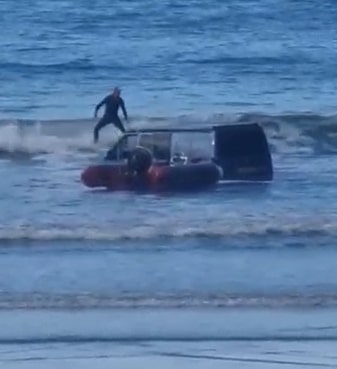 A surfer glides by the stranded van