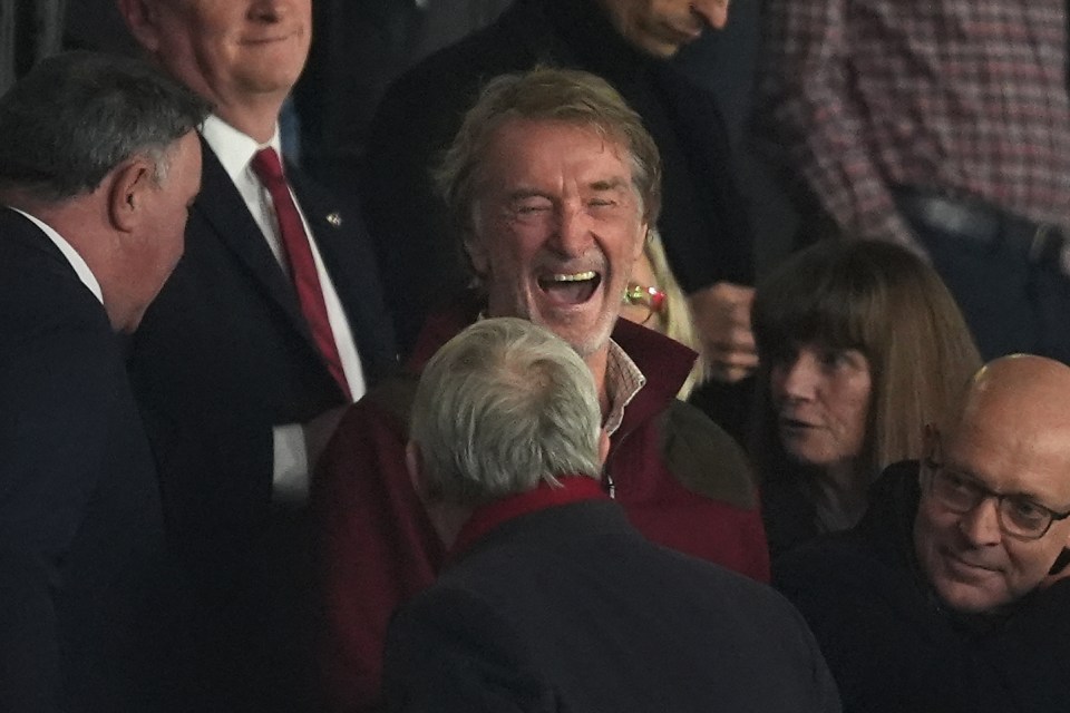 a man in a red jacket is laughing in a crowd