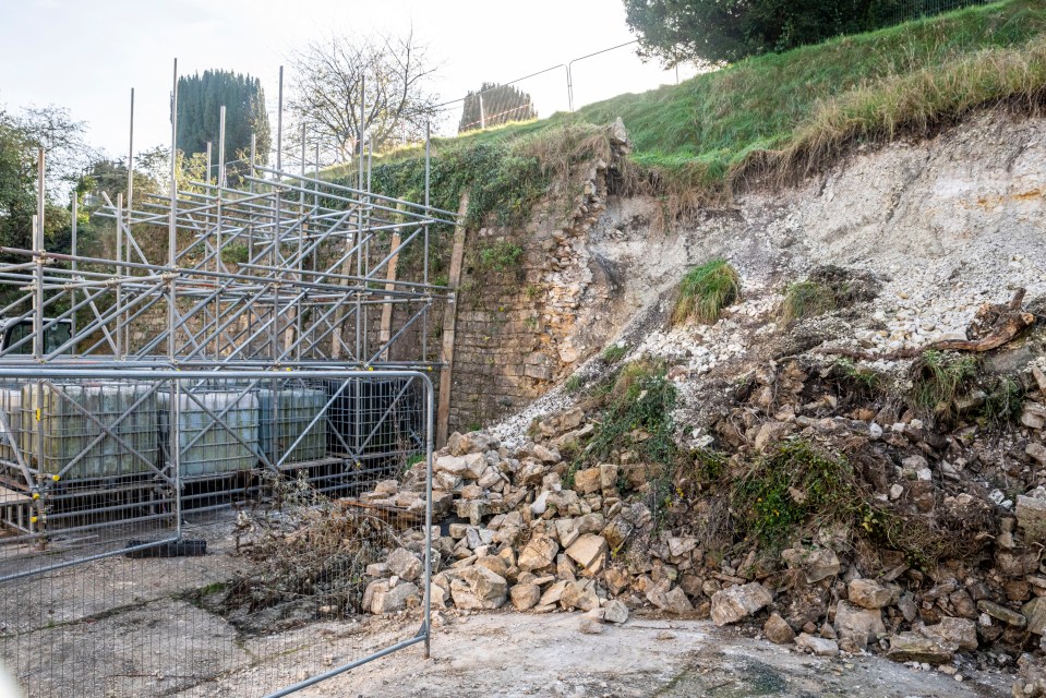 a pile of rocks sits in front of a fence and scaffolding