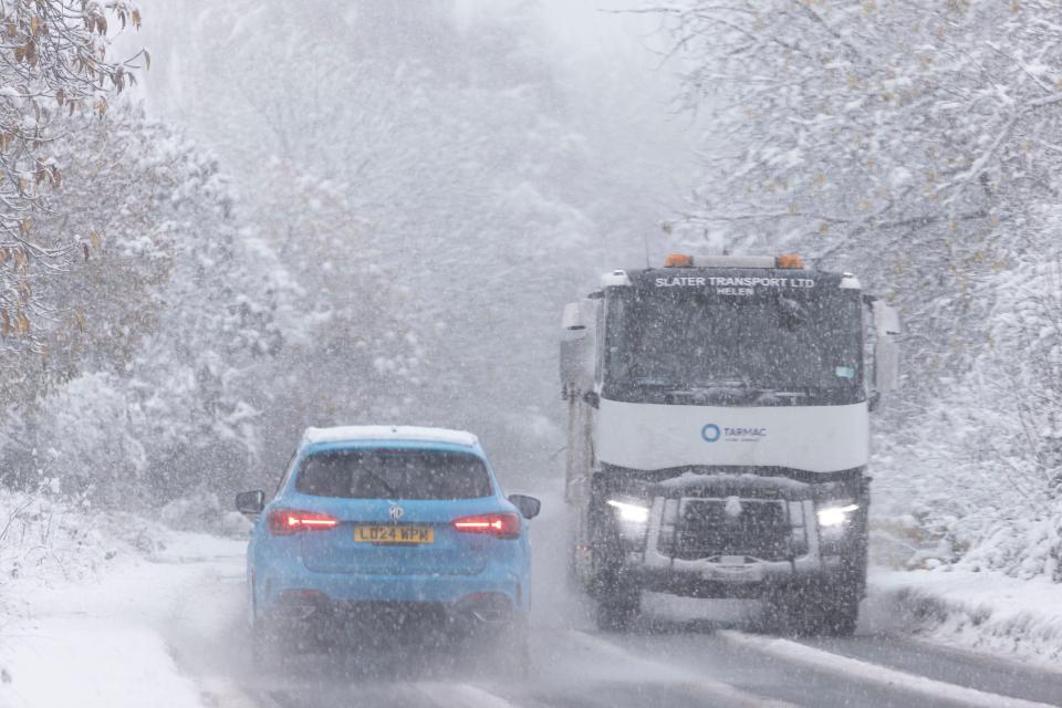 a car is driving down a snowy street at night