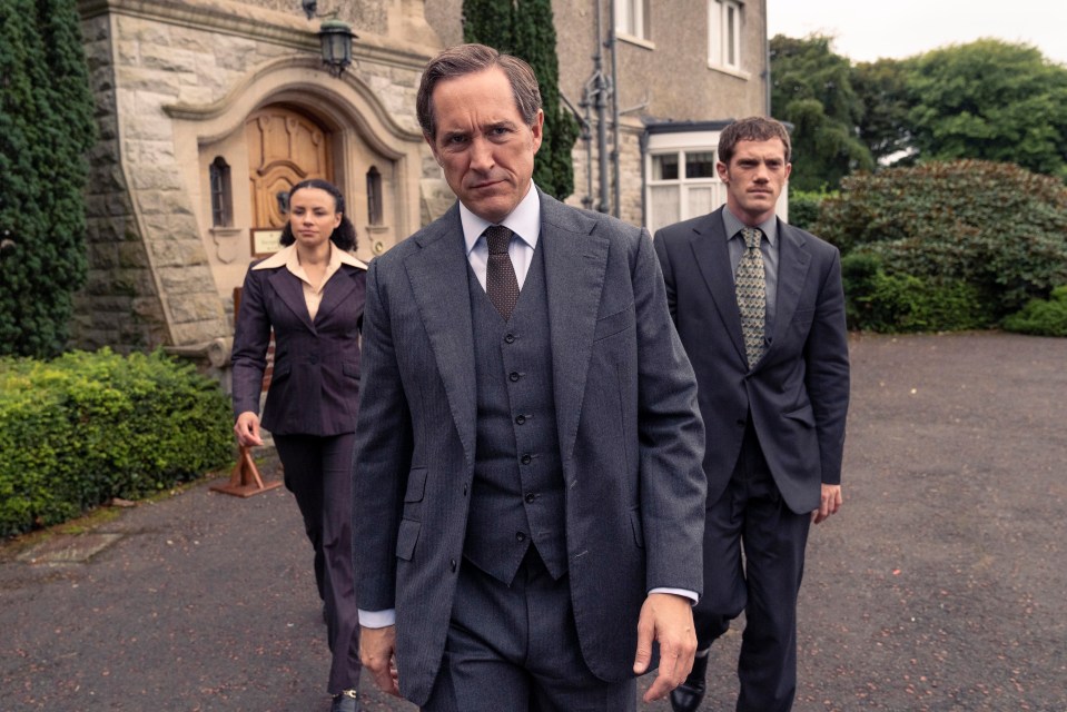 three men in suits and ties are walking in front of a building