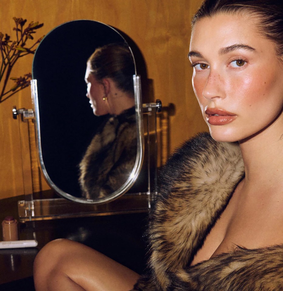 a woman in a fur coat sits in front of a mirror