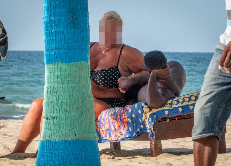 a woman in a bikini sits next to a man on a beach