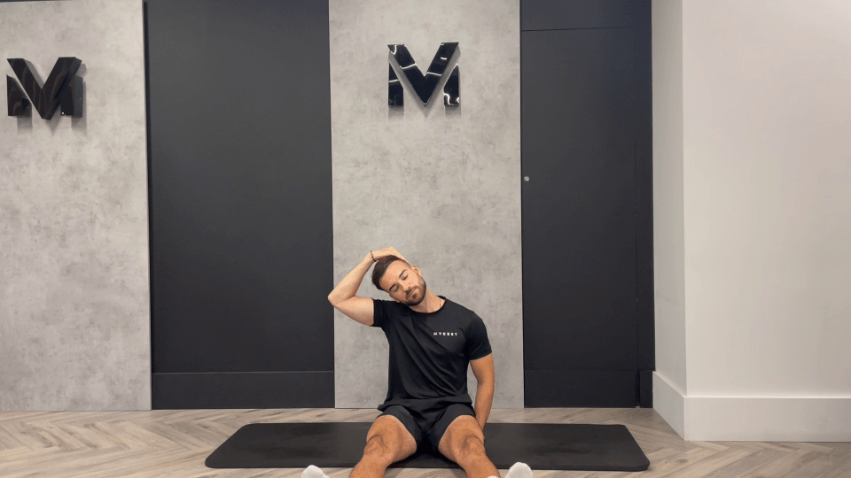 a man sits on a mat in front of a wall with the letter m on it