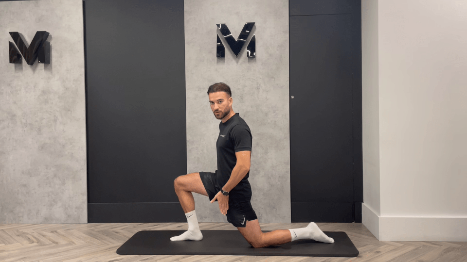 a man kneeling on a mat with the letter m behind him