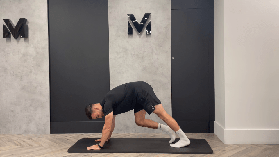 a man stands on a yoga mat in front of a wall with the letter m on it