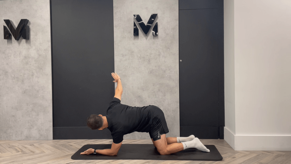 a man is kneeling on a mat in front of a wall with the letter m on it