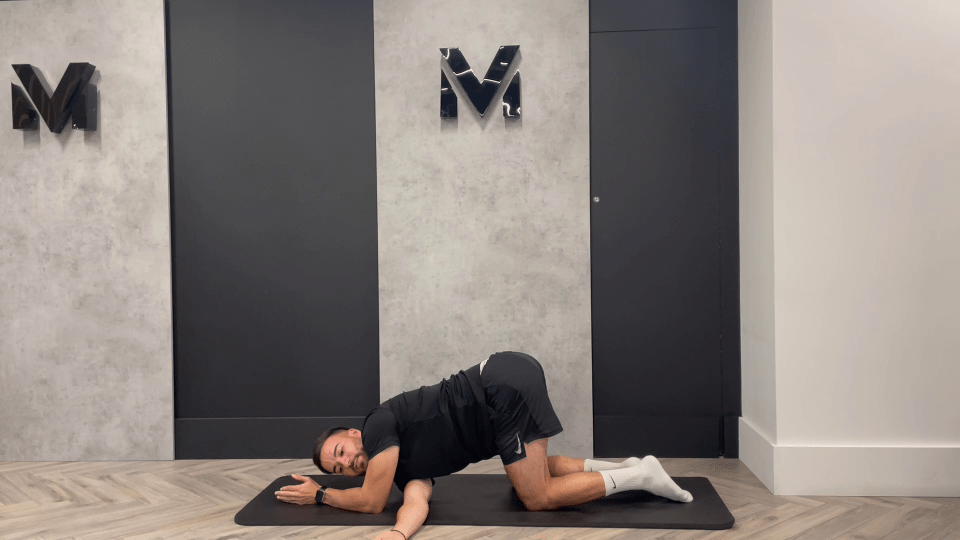 a man laying on a yoga mat in front of a wall with the letter m on it