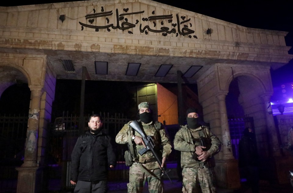 Syrian opposition fighters stand in front of University of Aleppo