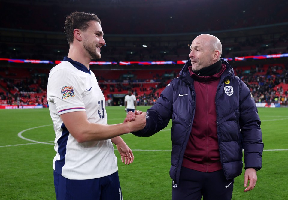 a man wearing a jacket that says england shakes hands with a soccer player