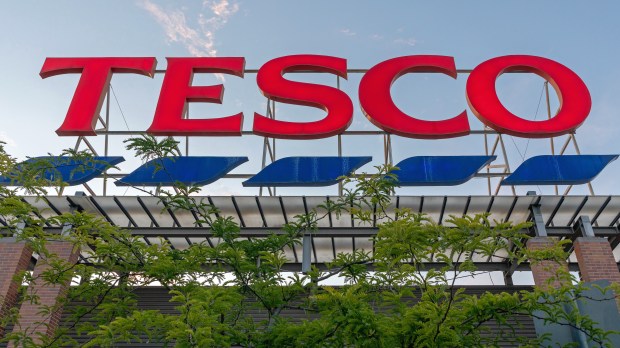 a large red tesco sign is surrounded by trees