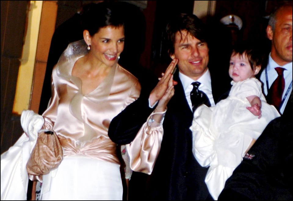 a man in a suit and tie holds a baby in a white dress