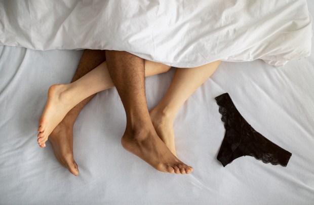 a man and a woman laying on a bed with a pair of black underwear