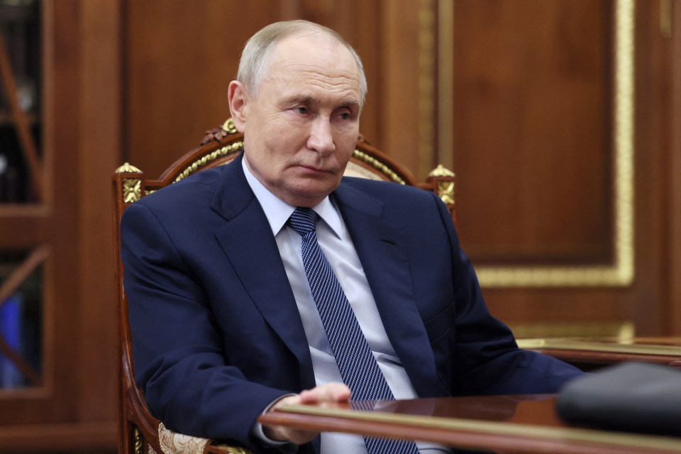 a man in a suit and tie sits at a desk