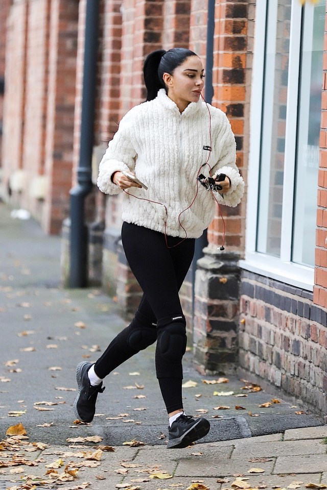 a woman wearing a white sweater and black leggings is running down a sidewalk