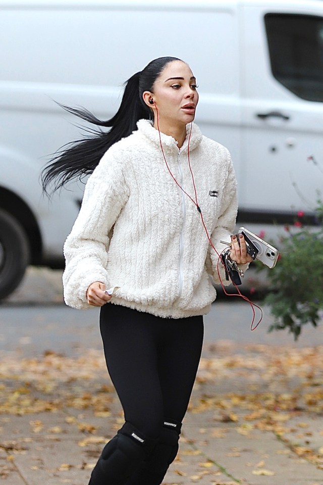 a woman wearing a white jacket and black leggings is running down the street