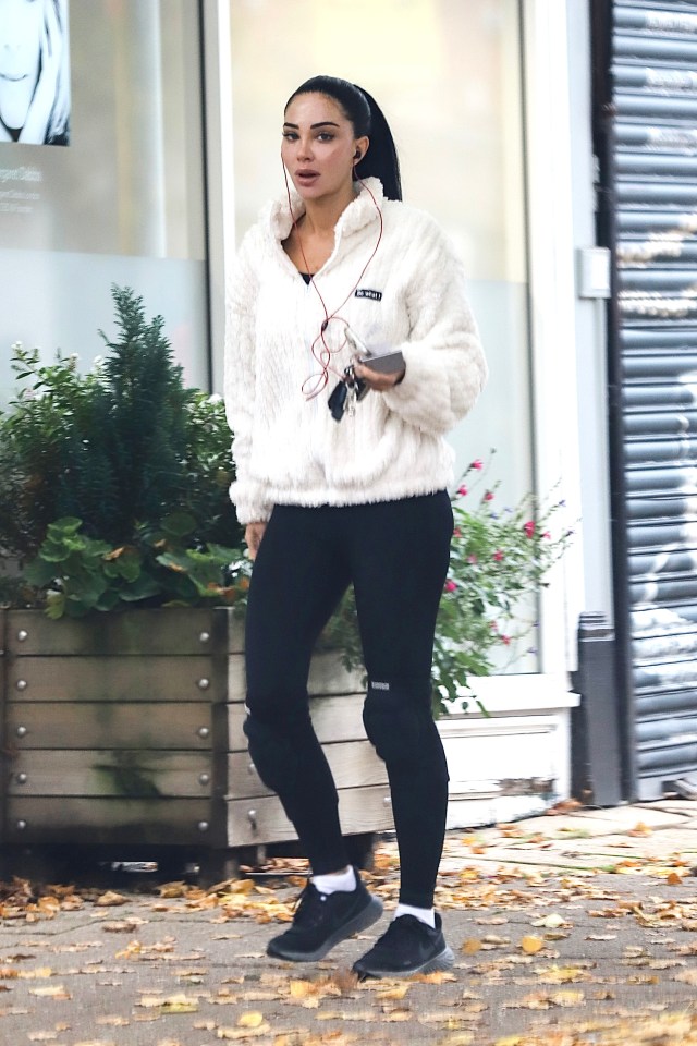 a woman wearing black leggings and a white jacket with the word reebok on it