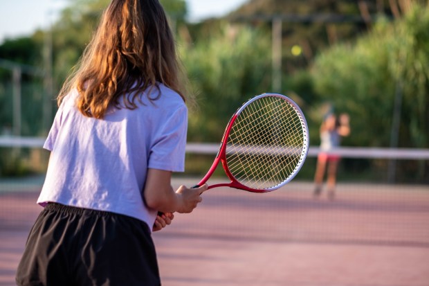 a girl in a purple shirt is holding a tennis racquet