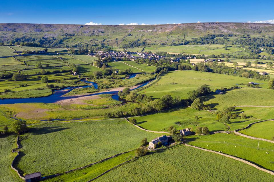 an aerial view of a lush green valley with a small village in the distance