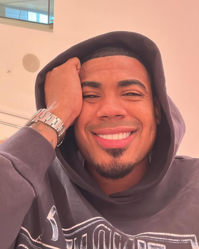 a man wearing a hoodie and a watch is smiling