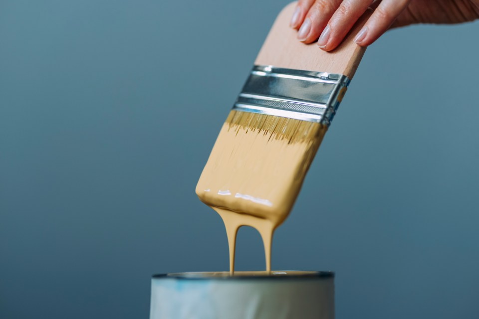 a person is pouring paint from a brush into a can