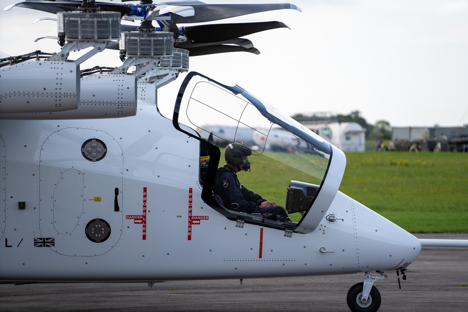 a man sits in the cockpit of a helicopter with a british flag on the side