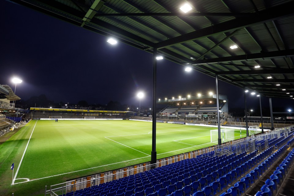 a soccer field is lit up at night with a stadium in the background