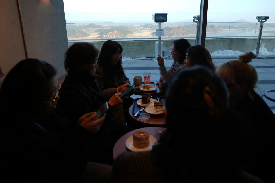 Visitors sit at a newly opened Starbucks store as North Korea’s Kaephung county is seen in the background